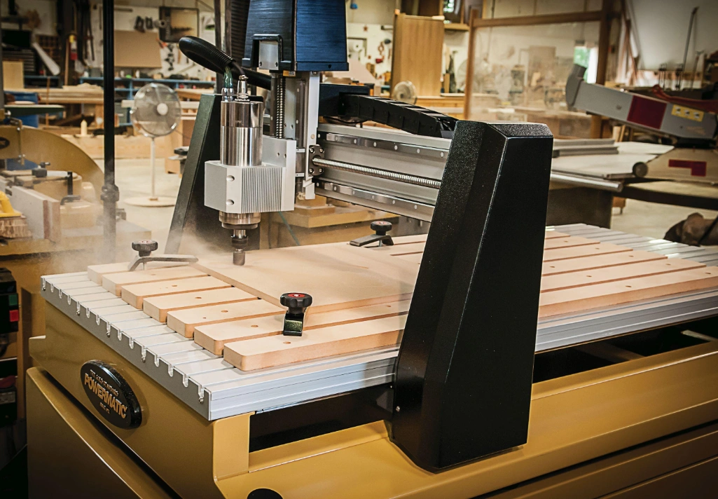 An image of a 3 axis CNC router machining a wooden block in a workshop  environment 