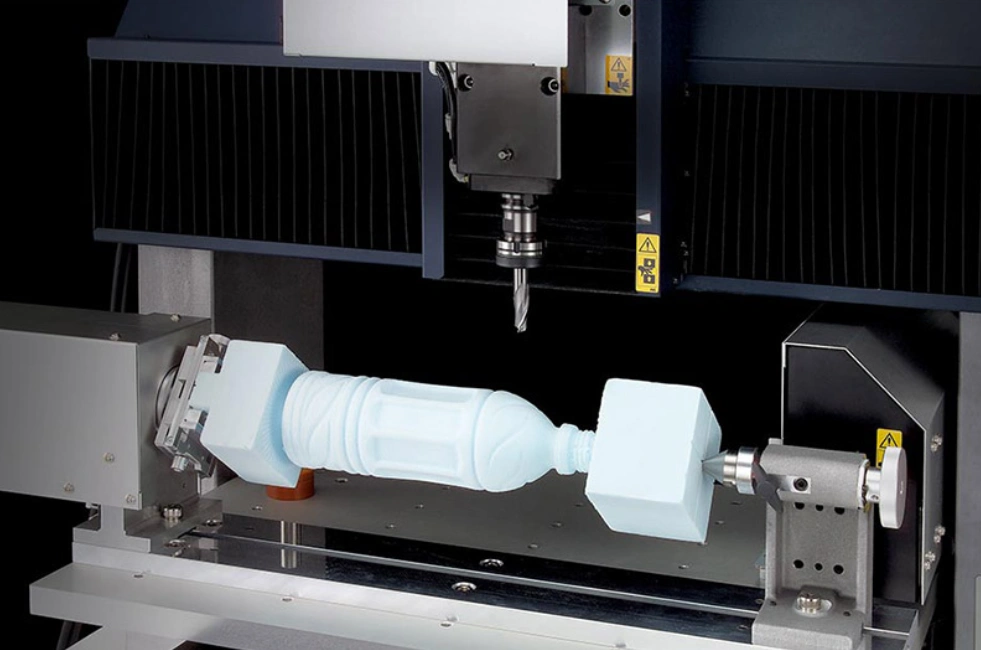 Image of 4-axis CNC machine with rotary axis machining a complex cylindrical workpiece