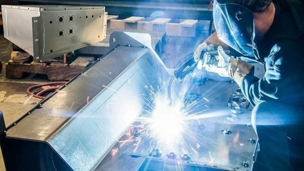 A close-up view of an operator welding the AC sheet metal enclosure