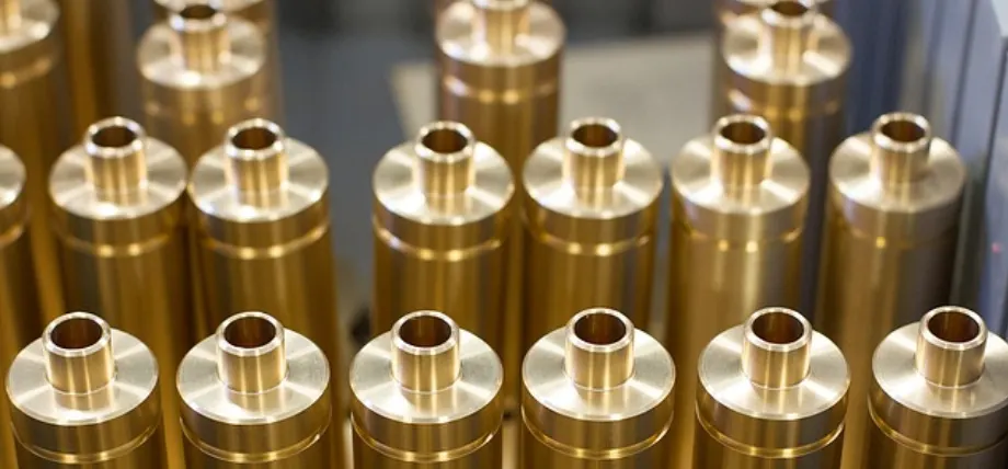 many cylindrical yellow chem film coated parts in a line