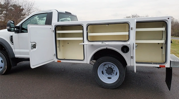 A white custom fabricated utility truck with side compartments open