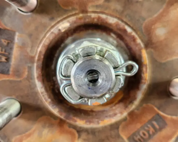 A metallic split pin visibly securing a wheel nut or axle component within a car wheel assembly 