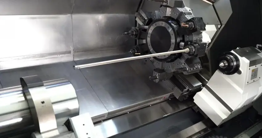 Industrial CNC lathe with turret tooling and long shaft workpiece in a drilling setup