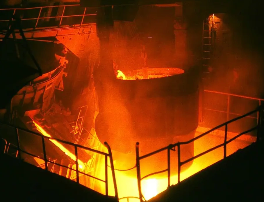 Molten metal being poured into an industrial furnace during the heat treatment process 
