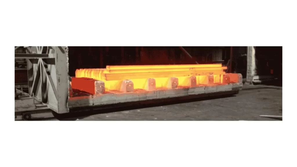 Steel bars undergoing the normalizing process, with a visible heat treatment effect.