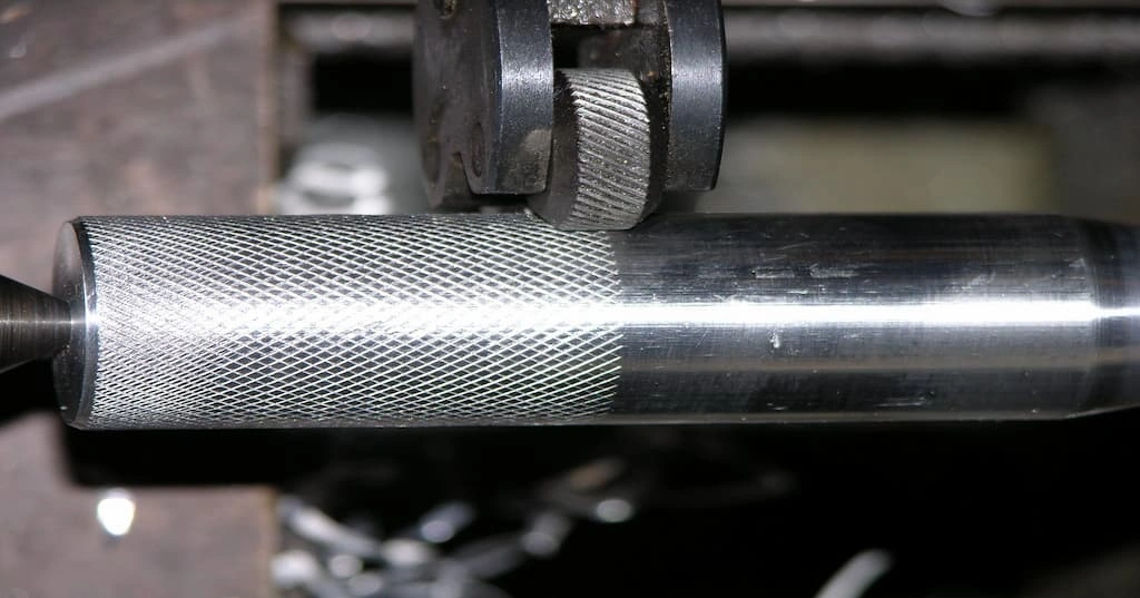 A close-up view of the knurling wheel imprinting the pattern on the workpiece surface 