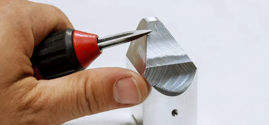 Manual tool deburring a metal piece with hand