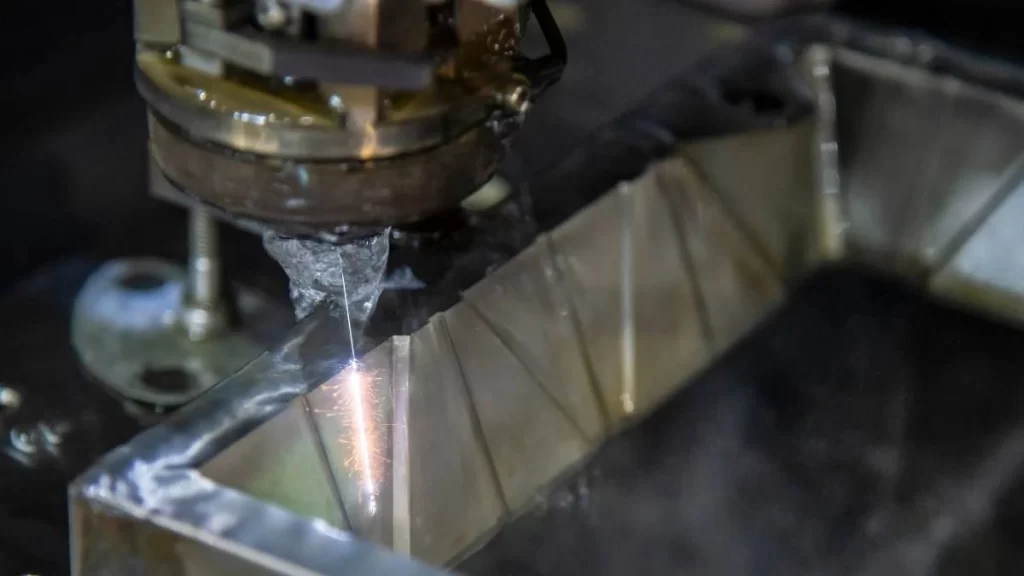 A depiction of the Wire EDM process in action. It shows a charged wire precisely cutting through steel and creating fine, accurate edges with no physical interaction