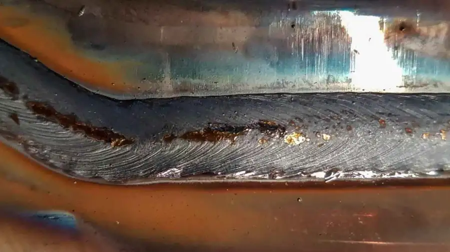 Close-up view of rusting on an aluminum weld, showing corrosion on the welded layer.