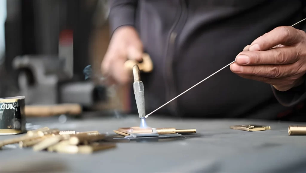 A technician soldering sheet metal parts with a heated tool.