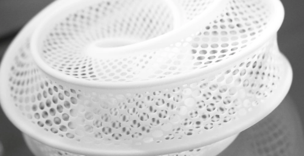 White 3D printed lattice structure with complex perforated geometry showcasing SLS manufacturing