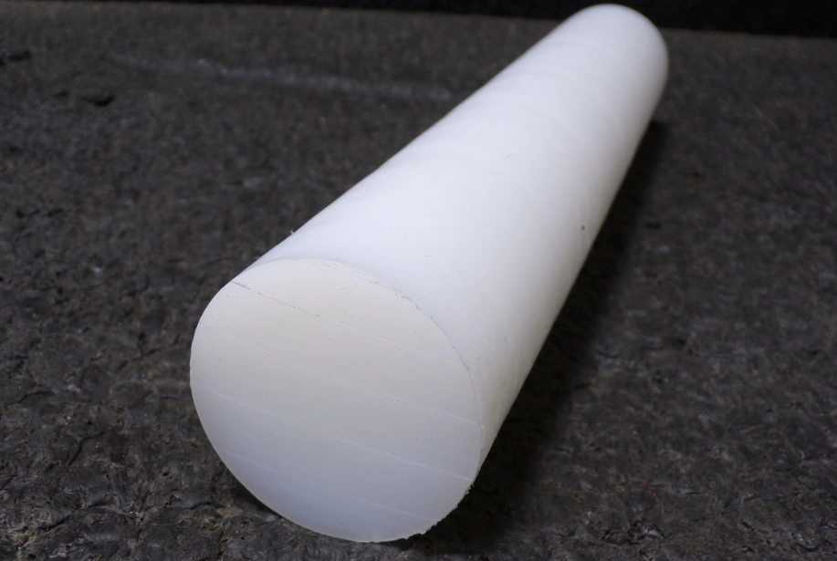 White UHMW polyethylene rod stock with smooth machined surface on dark textured background
